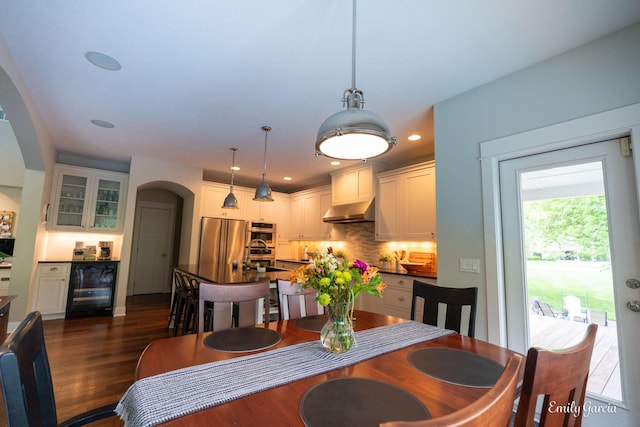 14921 Creek Edge Dr, Holland, MI 49424 - dining area with beverage cooler, arched walkways, dark wood-style floors, and recessed lighting