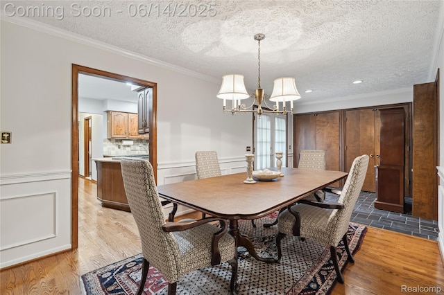 5614 Warbler Dr, Clarkston, MI 48346 - dining area featuring a chandelier, crown molding, a wainscoted wall, a textured ceiling, and wood finished floors