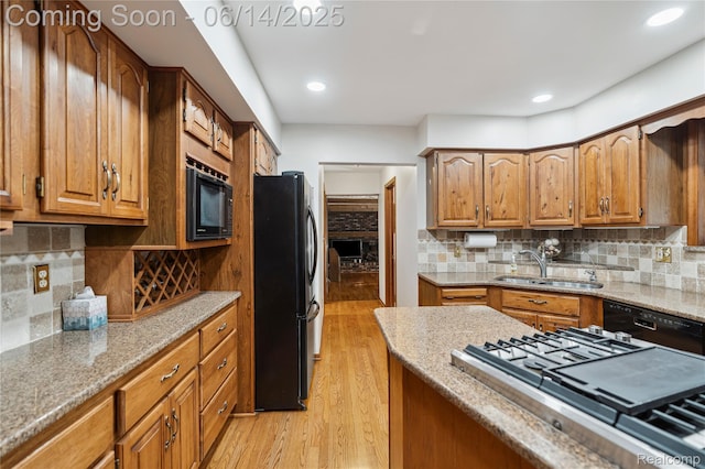 5614 Warbler Dr, Clarkston, MI 48346 - kitchen featuring black appliances, light wood-style floors, brown cabinets, light stone countertops, and backsplash