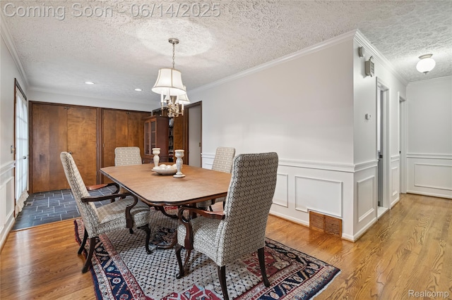 5614 Warbler Dr, Clarkston, MI 48346 - dining space with a textured ceiling, a chandelier, wood finished floors, a decorative wall, and wainscoting