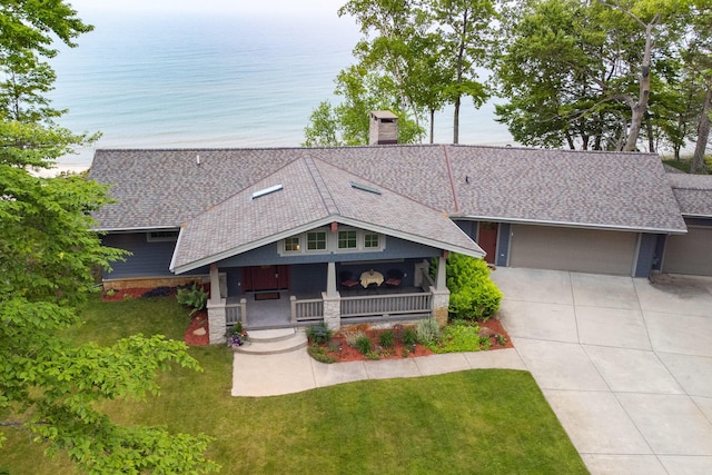 3524 Lakeshore Rd, Manistee, MI 49660 - craftsman house featuring covered porch, a chimney, a shingled roof, concrete driveway, and a front lawn