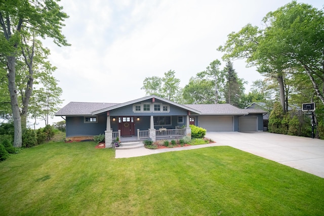 3524 Lakeshore Rd, Manistee, MI 49660 - craftsman-style house featuring a garage, a porch, concrete driveway, a front lawn, and roof with shingles