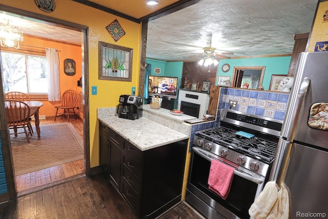33566 Rhonswood St, Farmington Hills, MI 48335 - kitchen with stainless steel appliances, a large fireplace, a ceiling fan, dark wood-style floors, and dark cabinetry