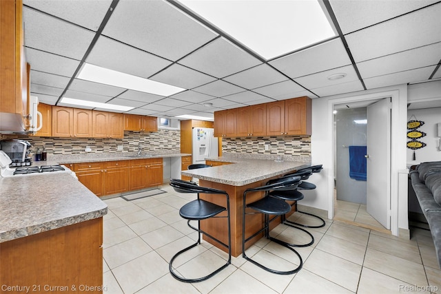 7561 Esper Blvd, Dearborn, MI 48126 - kitchen with white appliances, tasteful backsplash, a drop ceiling, brown cabinetry, and light tile patterned floors