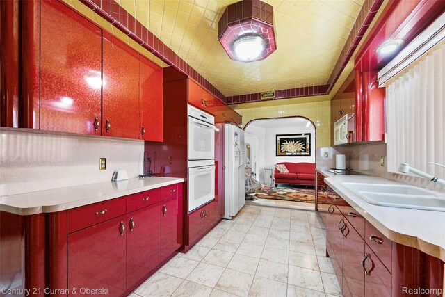 7561 Esper Blvd, Dearborn, MI 48126 - kitchen with red cabinets, white appliances, light countertops, and arched walkways