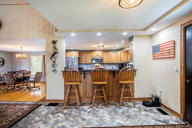 598 Dayburg Rd, Coldwater, MI 49036 - kitchen featuring appliances with stainless steel finishes, dark countertops, a breakfast bar area, decorative backsplash, and recessed lighting