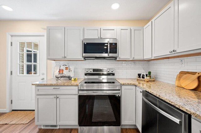 310 Hillview St, Buchanan, MI 49107 - kitchen featuring stainless steel appliances, tasteful backsplash, light stone countertops, wood finished floors, and recessed lighting