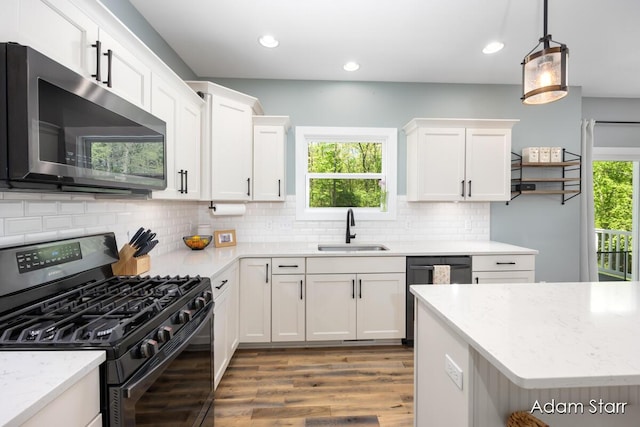 3980 Hathaway Rd, Kalamazoo, MI 49009 - kitchen with black gas range, stainless steel microwave, wood finished floors, white cabinetry, and recessed lighting
