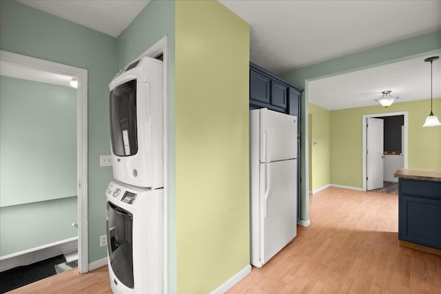 524 Kiddville St, Belding, MI 48809 - kitchen featuring freestanding refrigerator, stacked washer and clothes dryer, light wood finished floors, and decorative light fixtures