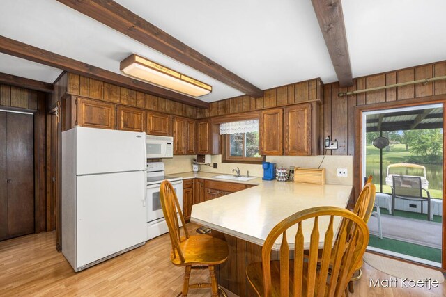 4410 Delaware Rd, Fremont, MI 49412 - kitchen with white appliances, light countertops, a peninsula, beamed ceiling, and a kitchen bar