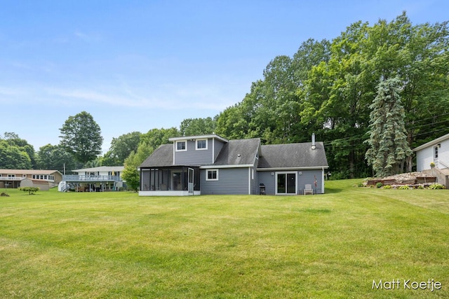 4410 Delaware Rd, Fremont, MI 49412 - rear view of house with a sunroom, a yard, roof with shingles, and view of scattered trees