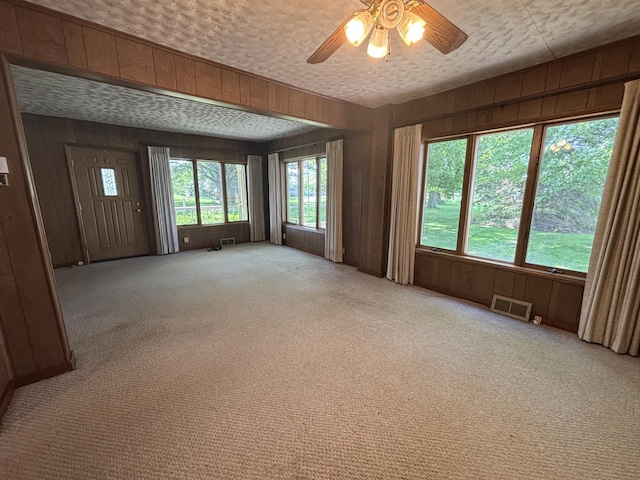 2523 E Wildcat, Saint Johns, MI 48879 - empty room featuring light colored carpet, wooden walls, and ceiling fan
