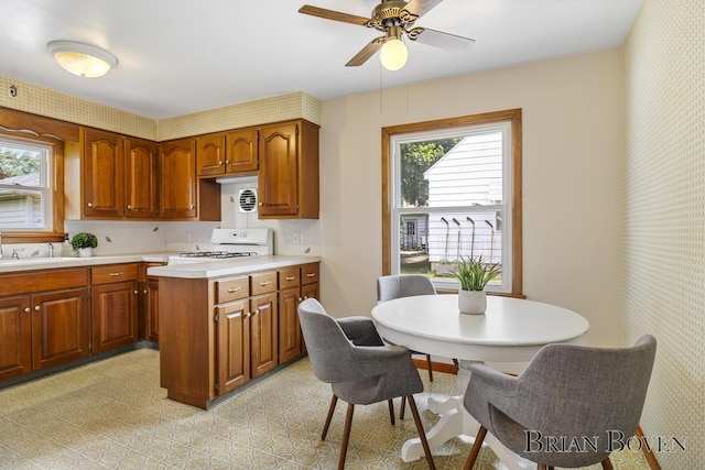 1665 7th St NW, Grand Rapids, MI 49504 - kitchen featuring white range oven, light countertops, wallpapered walls, healthy amount of natural light, and ceiling fan