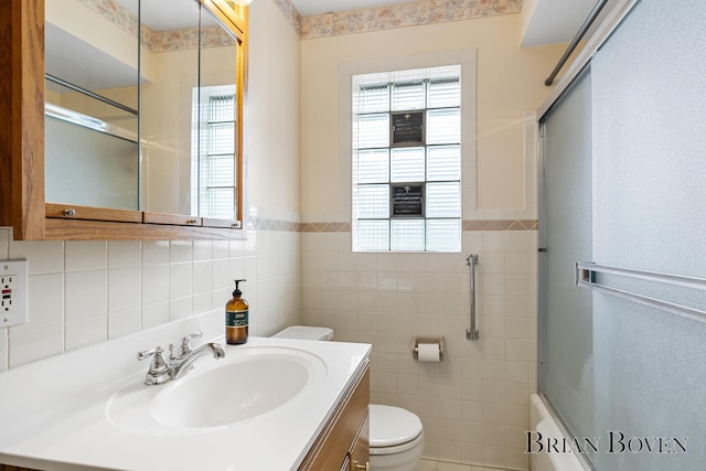 1665 7th St NW, Grand Rapids, MI 49504 - bathroom with tile walls, vanity, bath / shower combo with glass door, and wainscoting