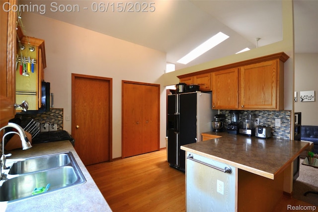 10010 Orchard Ridge Ct, Holly, MI 48442 - kitchen featuring light wood finished floors, tasteful backsplash, freestanding refrigerator, brown cabinetry, and vaulted ceiling