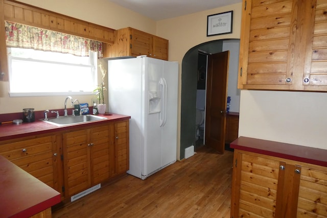 552 W Main St, Niles, MI 49120 - kitchen featuring white fridge with ice dispenser, light wood-style flooring, brown cabinets, and arched walkways