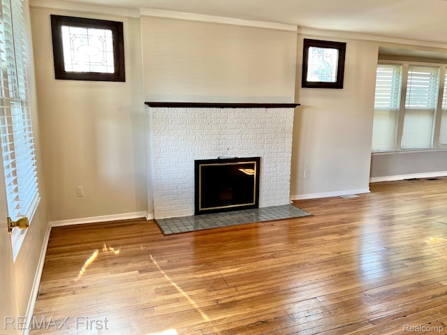 256 Withington St, Ferndale, MI 48220 - unfurnished living room featuring wood-type flooring, a brick fireplace, and crown molding