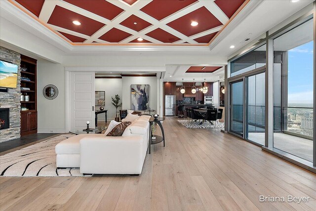 335 Bridge St NW Unit 3102, Grand Rapids, MI 49504 - living room featuring a stone fireplace, light wood-style floors, crown molding, coffered ceiling, and recessed lighting