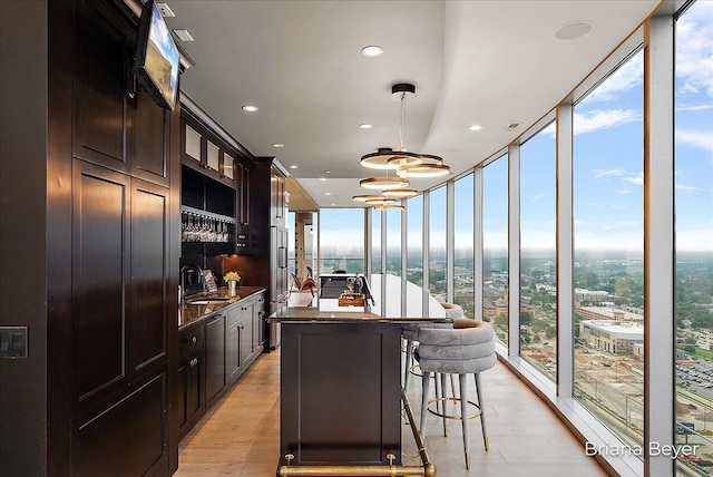 335 Bridge St NW Unit 3102, Grand Rapids, MI 49504 - kitchen with floor to ceiling windows, a kitchen island, light wood-type flooring, dark countertops, and hanging light fixtures