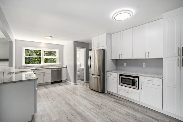 6737 Cypress St, Portage, MI 49024 - kitchen featuring stainless steel appliances, light stone counters, light wood-style floors, white cabinets, and tasteful backsplash