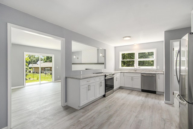 6737 Cypress St, Portage, MI 49024 - kitchen featuring stainless steel appliances, light wood-type flooring, light stone counters, white cabinetry, and backsplash