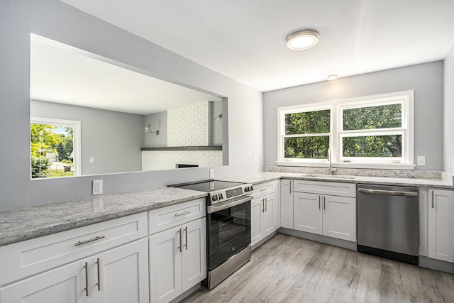 6737 Cypress St, Portage, MI 49024 - kitchen featuring appliances with stainless steel finishes, light wood-type flooring, light stone countertops, white cabinets, and backsplash