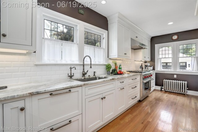 11 Sylvan Ave, Pleasant Ridge, MI 48069 - kitchen featuring radiator heating unit, luxury range, white cabinets, exhaust hood, and light wood finished floors