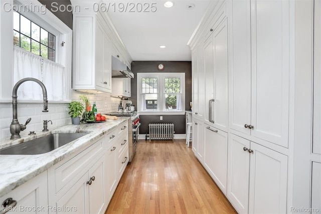 11 Sylvan Ave, Pleasant Ridge, MI 48069 - kitchen featuring radiator, stainless steel stove, white cabinets, under cabinet range hood, and light wood finished floors