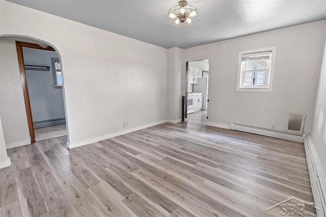 490 W Wilder Rd, Auburn, MI 48611 - spare room featuring a baseboard heating unit, arched walkways, a baseboard radiator, and light wood finished floors