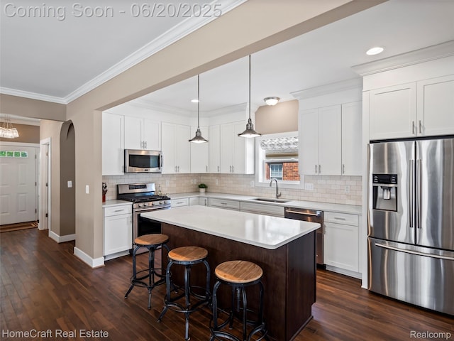 2213 Beverly Blvd, Berkley, MI 48072 - kitchen featuring appliances with stainless steel finishes, a kitchen bar, light countertops, dark wood-type flooring, and a center island
