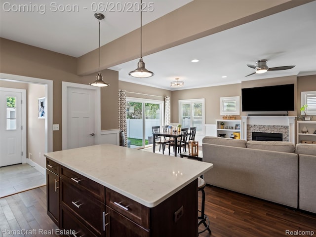 2213 Beverly Blvd, Berkley, MI 48072 - kitchen featuring a breakfast bar area, dark wood-style flooring, dark brown cabinetry, a ceiling fan, and a fireplace