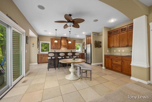 2331 Deer Trail Dr NE, Grand Rapids, MI 49505 - kitchen featuring stainless steel refrigerator with ice dispenser, tasteful backsplash, brown cabinetry, a kitchen bar, and a ceiling fan