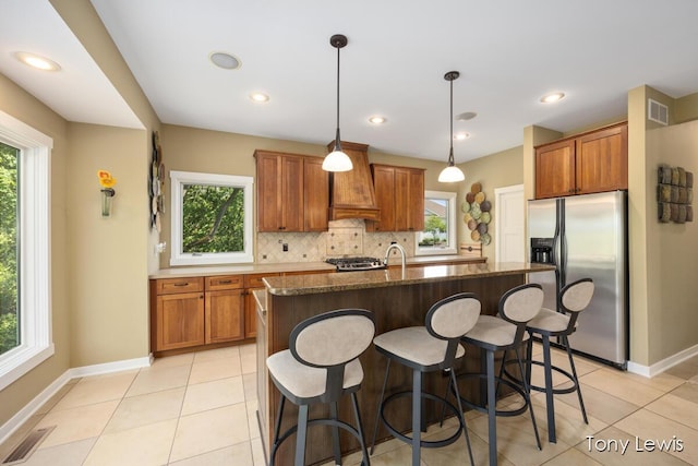 2331 Deer Trail Dr NE, Grand Rapids, MI 49505 - kitchen featuring stainless steel appliances, custom exhaust hood, brown cabinetry, tasteful backsplash, and light tile patterned flooring