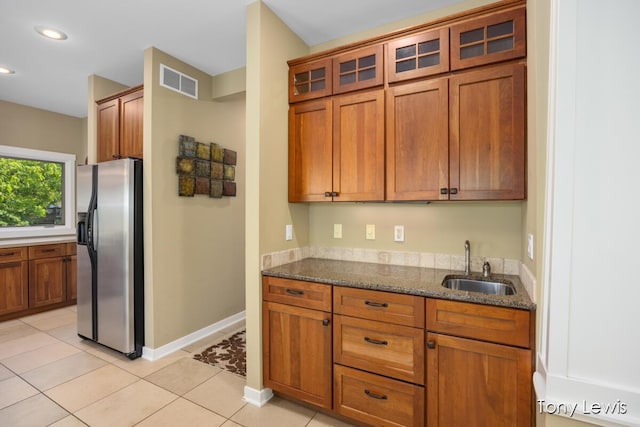 2331 Deer Trail Dr NE, Grand Rapids, MI 49505 - kitchen featuring stainless steel fridge with ice dispenser, brown cabinetry, dark stone countertops, glass insert cabinets, and recessed lighting