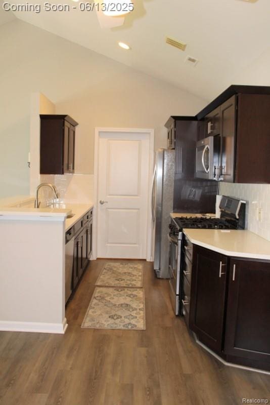 23413 Williamsburg Cir Unit 12, Woodhaven, MI 48183 - kitchen with stainless steel appliances, vaulted ceiling, decorative backsplash, dark brown cabinetry, and dark wood-type flooring