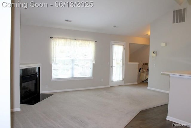 23413 Williamsburg Cir Unit 12, Woodhaven, MI 48183 - unfurnished living room featuring a fireplace with flush hearth and carpet