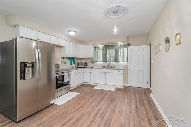 1601 S Monroe St, Bay City, MI 48708 - kitchen with stainless steel appliances, white cabinetry, light wood finished floors, and pendant lighting