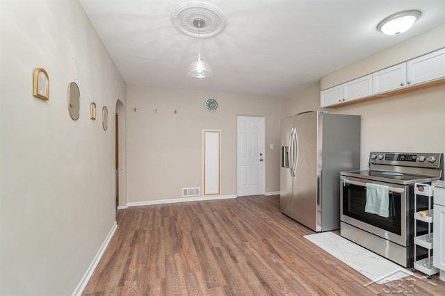 1601 S Monroe St, Bay City, MI 48708 - kitchen featuring stainless steel appliances, wood finished floors, white cabinets, and arched walkways