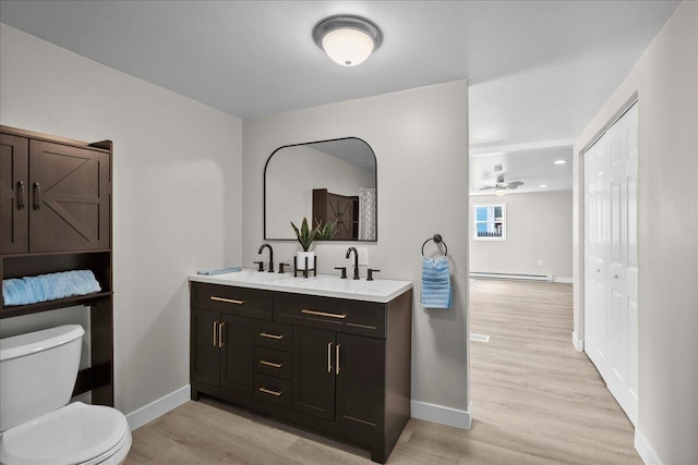 1178 Drent Rd, Muskegon, MI 49442 - full bathroom with double vanity, a baseboard heating unit, wood finished floors, ceiling fan, and recessed lighting