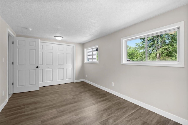 1178 Drent Rd, Muskegon, MI 49442 - unfurnished bedroom with dark wood-type flooring, a textured ceiling, and a closet
