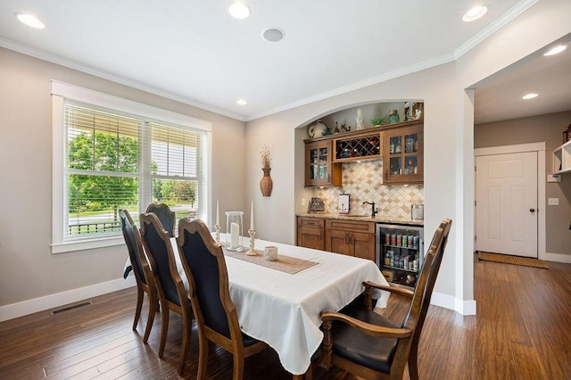 2753 Colton Dr, Berrien Springs, MI 49103 - dining space featuring wine cooler, wet bar, dark wood-type flooring, crown molding, and recessed lighting