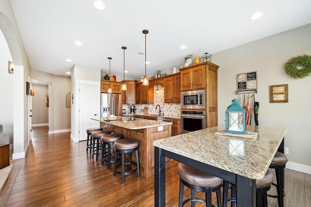 2753 Colton Dr, Berrien Springs, MI 49103 - kitchen with stainless steel appliances, brown cabinetry, a breakfast bar area, dark wood-style floors, and tasteful backsplash