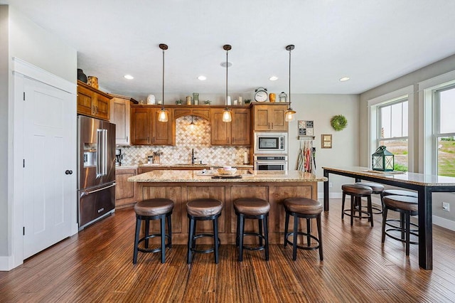 2753 Colton Dr, Berrien Springs, MI 49103 - kitchen with stainless steel appliances, dark wood-style floors, tasteful backsplash, a kitchen island, and brown cabinetry