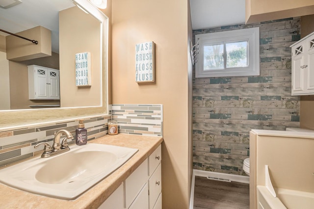 3923 Perry Ave SW, Wyoming, MI 49519 - full bath with wooden walls, vanity, wood finished floors, and backsplash