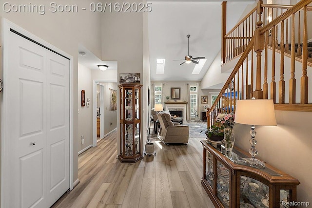 372 Four Seasons Dr, Lake Orion, MI 48360 - living room featuring high vaulted ceiling, ceiling fan, a warm lit fireplace, stairway, and light wood-style flooring