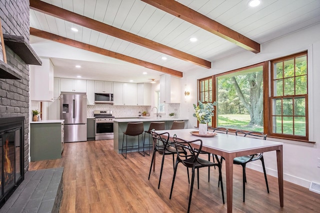 3737 Peach Ridge Ave NW, Grand Rapids, MI 49544 - dining area featuring a brick fireplace, wood finished floors, beam ceiling, and recessed lighting