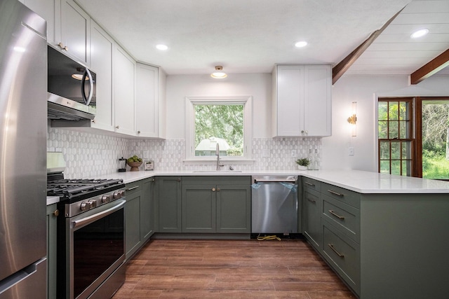 3737 Peach Ridge Ave NW, Grand Rapids, MI 49544 - kitchen featuring appliances with stainless steel finishes, a peninsula, plenty of natural light, white cabinets, and beam ceiling