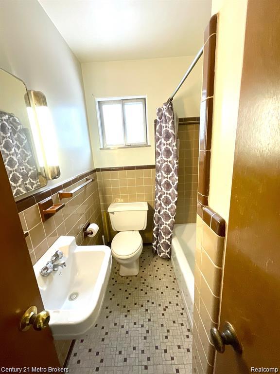 106 N Marquette St, Durand, MI 48429 - full bathroom featuring tile walls, wainscoting, and shower / tub combo