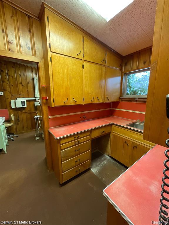 106 N Marquette St, Durand, MI 48429 - kitchen featuring built in study area, brown cabinets, and wooden walls