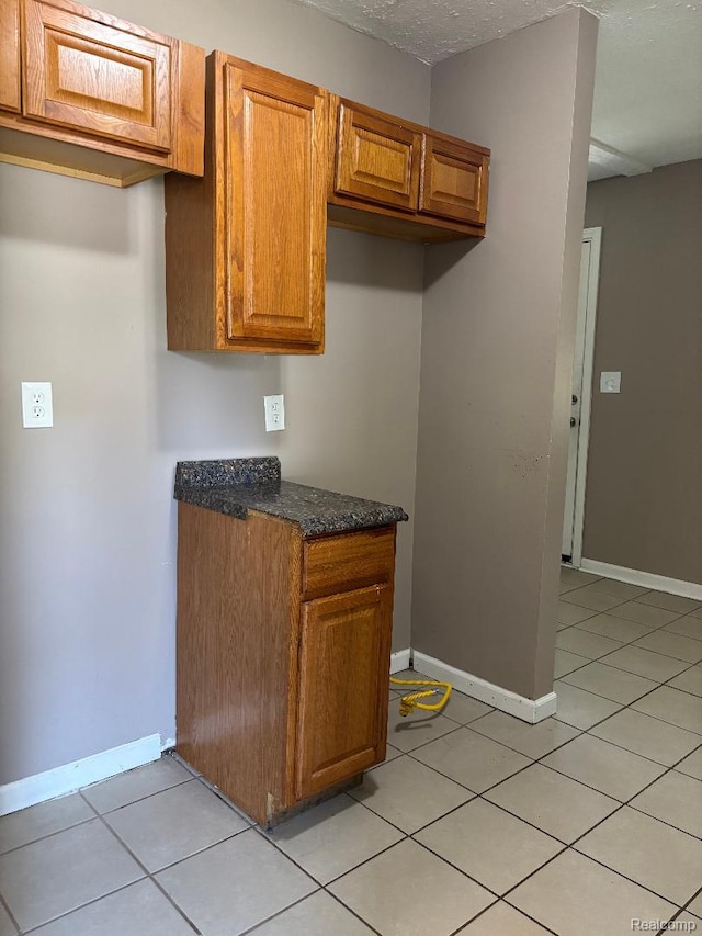 6303 Duncan St, Taylor, MI 48180 - kitchen featuring brown cabinetry, dark stone countertops, and light tile patterned flooring